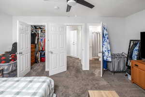 Bedroom featuring connected bathroom, a closet, ceiling fan, and dark colored carpet