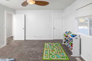 Game room featuring dark colored carpet and ceiling fan