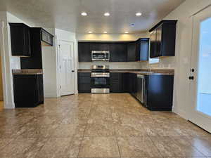 Kitchen featuring light tile patterned flooring, appliances with stainless steel finishes, sink, and a textured ceiling