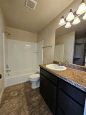 Full bathroom with vanity, a textured ceiling,  shower combination, and toilet