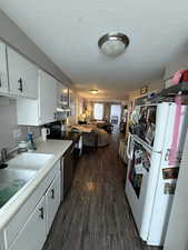 Kitchen featuring white cabinetry, sink, white fridge, dark wood-type flooring, and a textured ceiling