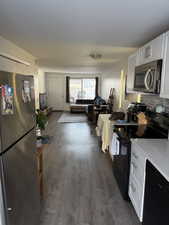 Kitchen with white cabinets, dark hardwood / wood-style floors, decorative backsplash, and black appliances