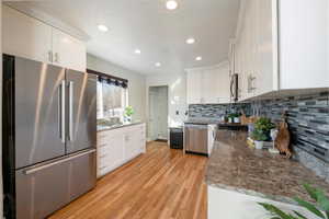 Kitchen featuring white cabinetry, appliances with stainless steel finishes, stone countertops, and decorative backsplash