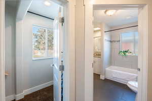 Bathroom with tiled shower / bath, plenty of natural light, and toilet