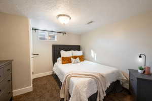 Bedroom with dark carpet and a textured ceiling