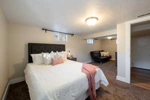 Bedroom with a textured ceiling and dark carpet