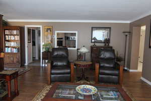 Living room featuring ornamental molding and dark hardwood / wood-style flooring