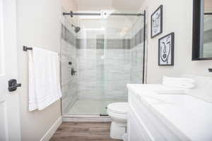 Bathroom featuring vanity, toilet, a shower with shower door, and wood-type flooring