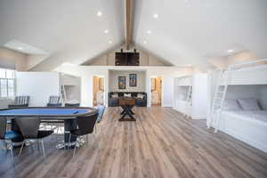 Game room with high vaulted ceiling, hardwood / wood-style floors, and beam ceiling