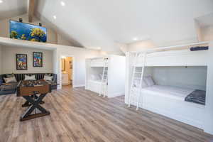 Bedroom with ensuite bathroom, lofted ceiling with beams, and light wood-type flooring