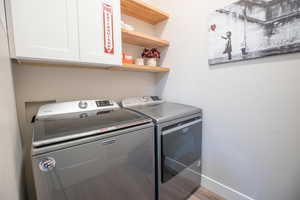 Washroom with cabinets and washing machine and clothes dryer