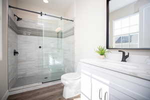 Bathroom featuring walk in shower, vanity, toilet, and hardwood / wood-style floors