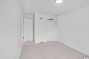 Unfurnished bedroom with light colored carpet and a closet