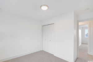 Unfurnished bedroom with light colored carpet and a closet