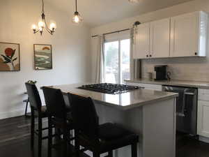 Kitchen featuring white cabinetry, a kitchen bar, black dishwasher, and a kitchen island