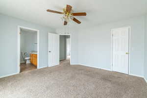 Unfurnished bedroom featuring light carpet, ensuite bath, and ceiling fan