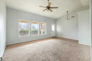 Carpeted spare room with ceiling fan and vaulted ceiling