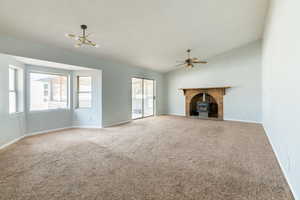 Unfurnished living room with lofted ceiling, ceiling fan with notable chandelier, carpet floors, and a healthy amount of sunlight