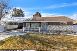 Single story home featuring a carport, covered porch, and a front lawn