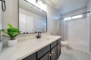 Full bathroom with shower / bath combination with curtain, tile patterned floors, vanity, and toilet