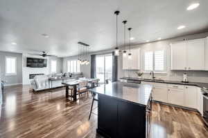 Kitchen featuring white cabinetry, a kitchen island, dark hardwood / wood-style floors, and pendant lighting