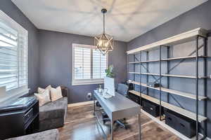 Office area featuring a healthy amount of sunlight, dark wood-type flooring, and a chandelier