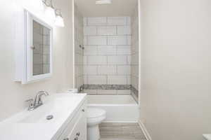 Full bathroom featuring hardwood / wood-style flooring, vanity, toilet, and tiled shower / bath combo