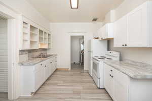 Kitchen featuring white cabinets, sink, electric range, and light hardwood / wood-style flooring