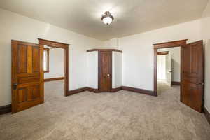 Unfurnished bedroom with light colored carpet and a textured ceiling