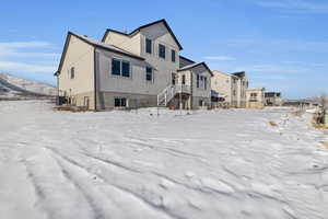 Snow covered rear of property featuring cooling unit and central air condition unit