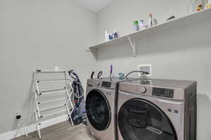 Clothes washing area featuring wood-type flooring and washing machine and clothes dryer