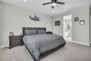 Bedroom with ceiling fan, ensuite bathroom, and light carpet