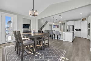 Dining area featuring lofted ceiling, dark wood-type flooring, and a chandelier