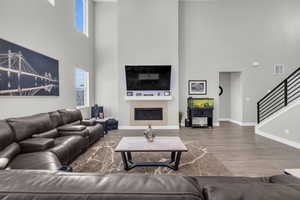 Living room with a high ceiling, hardwood / wood-style floors, and a fireplace