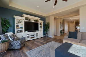 Living room featuring a tray ceiling, dark hardwood / wood-style floors, and ceiling fan