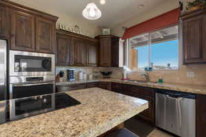 Kitchen featuring dark brown cabinetry, sink, decorative light fixtures, and appliances with stainless steel finishes