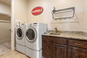 Clothes washing area featuring sink, washer and clothes dryer, cabinets, and light tile patterned flooring