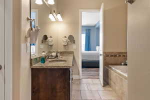 Bathroom with vanity, tiled bath, and tile patterned floors