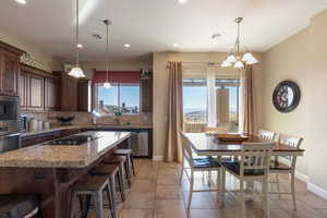 Kitchen featuring dark brown cabinets, stainless steel appliances, a kitchen island, light tile patterned flooring, and decorative backsplash