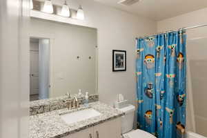 Full bathroom featuring shower / bathtub combination with curtain, vanity, and toilet