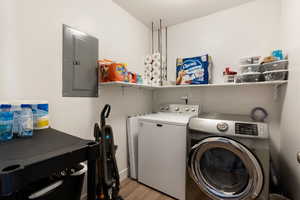 Laundry area featuring separate washer and dryer, electric panel, and light hardwood / wood-style floors