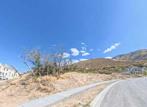View of asphalt road with sidewalks, curbs, and a mountain view