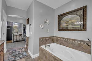 Bathroom with tile patterned flooring, vanity, and a relaxing tiled tub