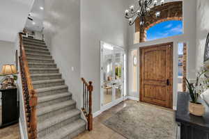 Tiled foyer featuring a towering ceiling and a notable chandelier