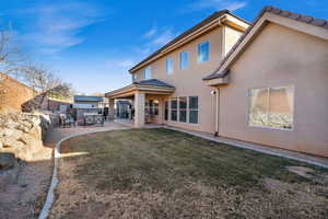 Rear view of property featuring a yard and a patio area