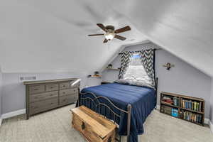 Carpeted bedroom featuring a textured ceiling, vaulted ceiling, and ceiling fan