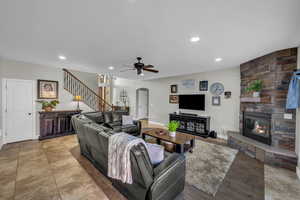 Living room with a fireplace, light hardwood / wood-style floors, and ceiling fan