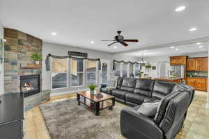 Living room with sink, ceiling fan with notable chandelier, a fireplace, and light hardwood / wood-style flooring