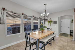 Tiled dining room with a chandelier