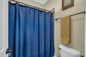 Bathroom with a shower with curtain and toilet